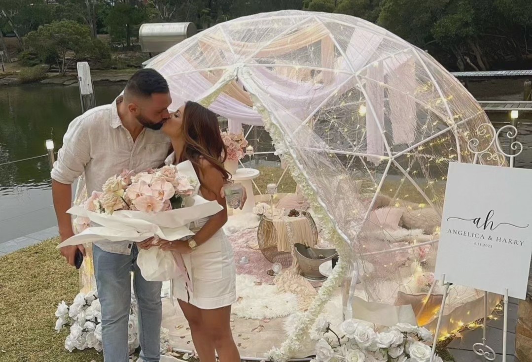 Couple kissing in front of a pink draped IGLOOZE dome by the water
